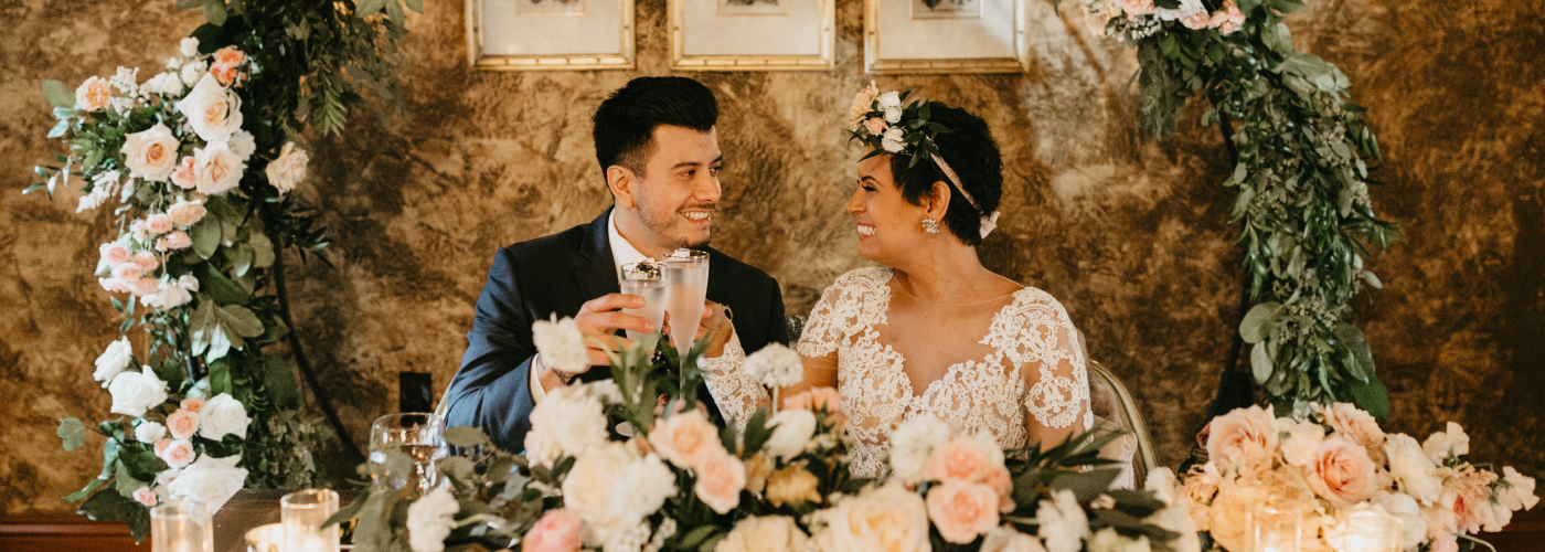smiling wedding couple seated toasting champagne